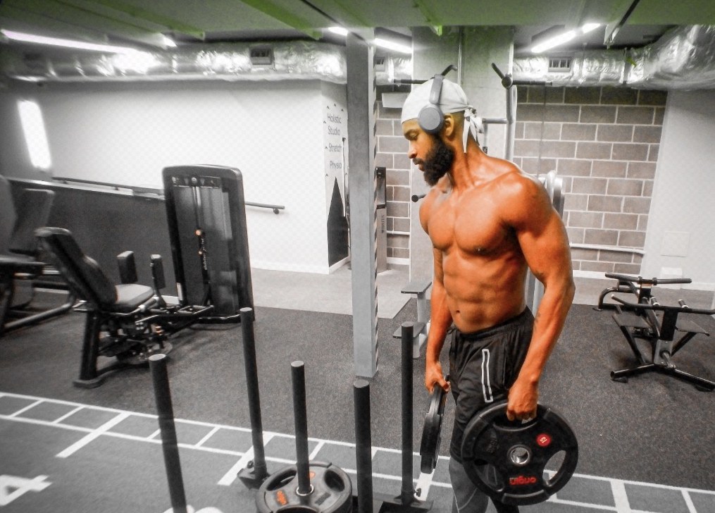 Haqq carrying weight plates in the gym